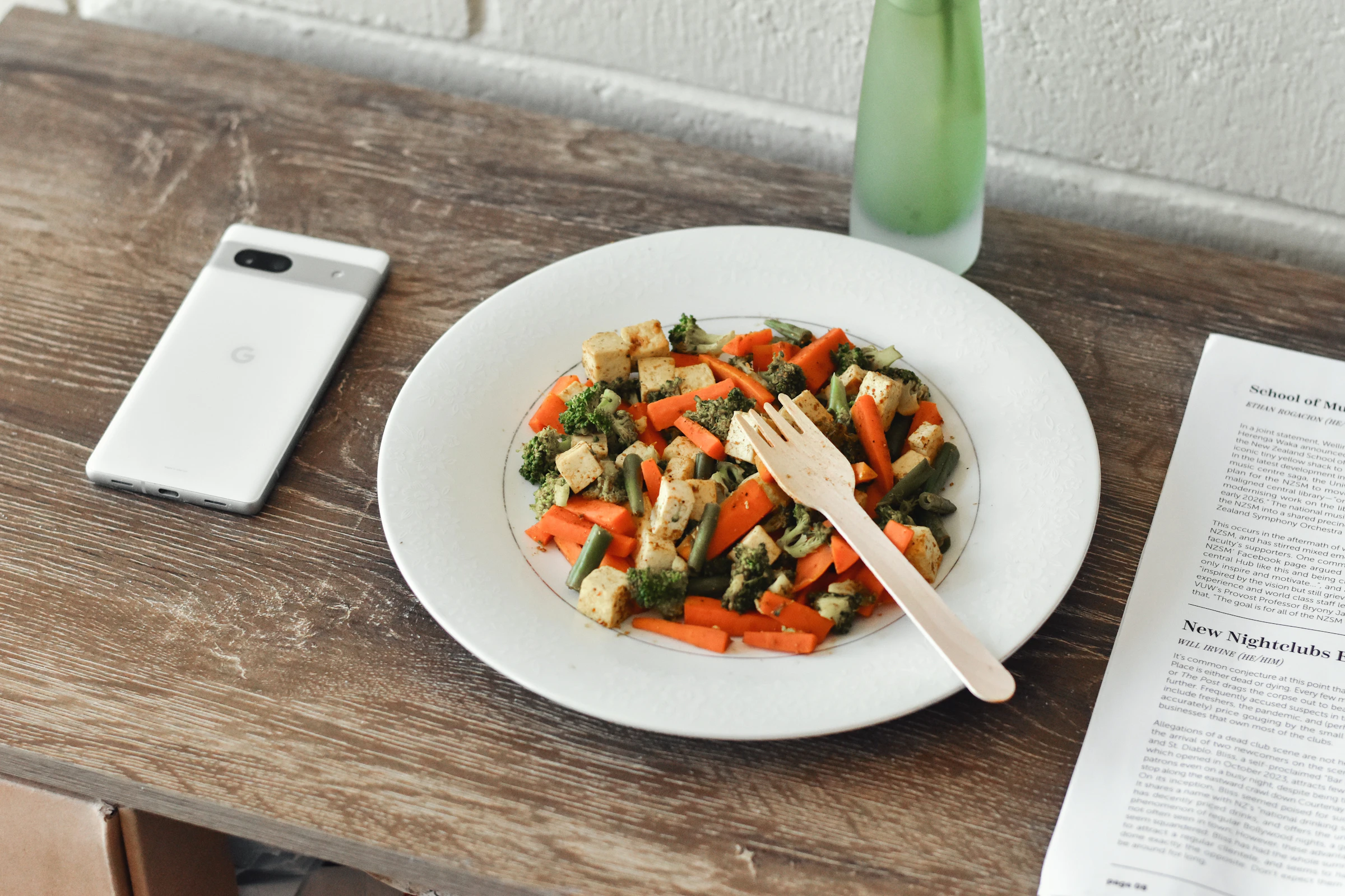A plate of food next to a smartphone running a nutrition app,