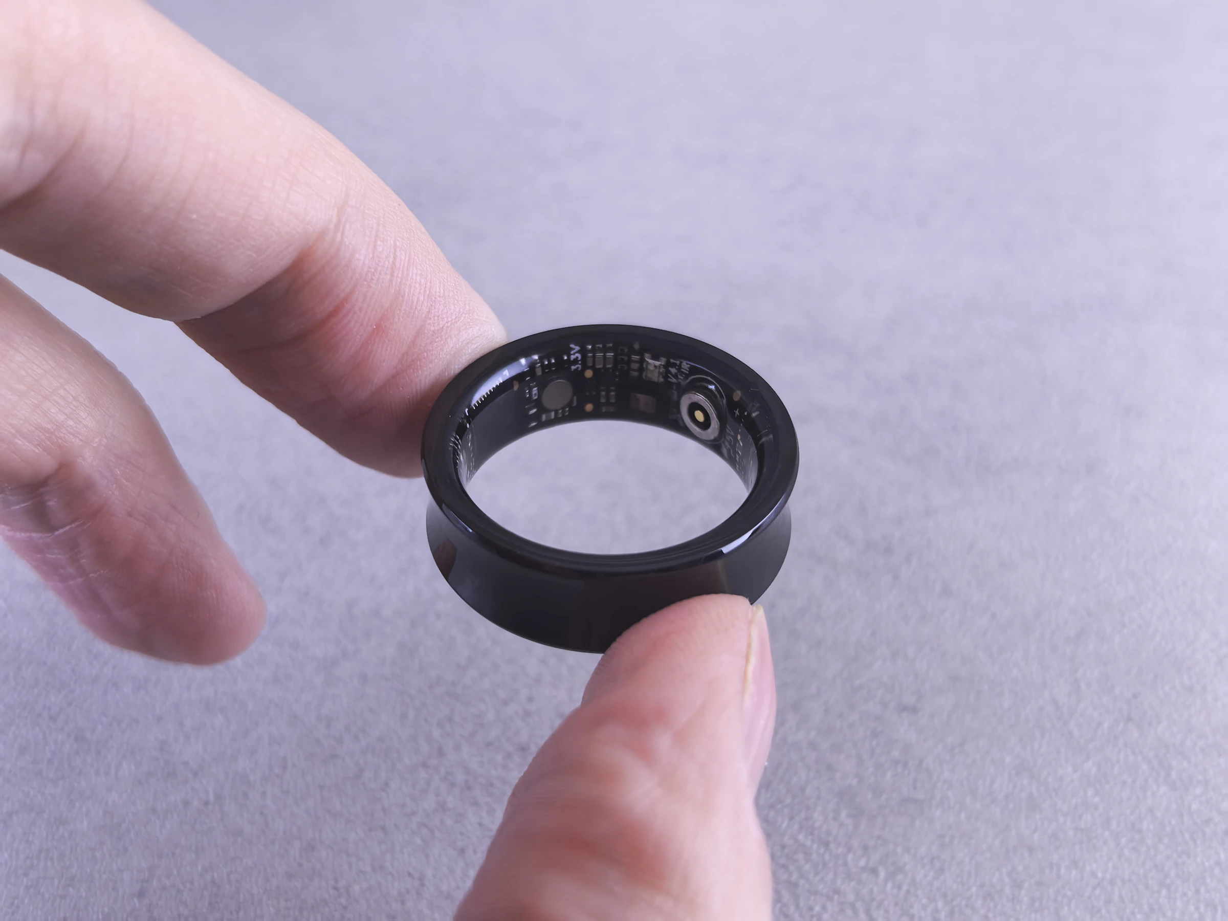 A black smart ring held between two fingers,