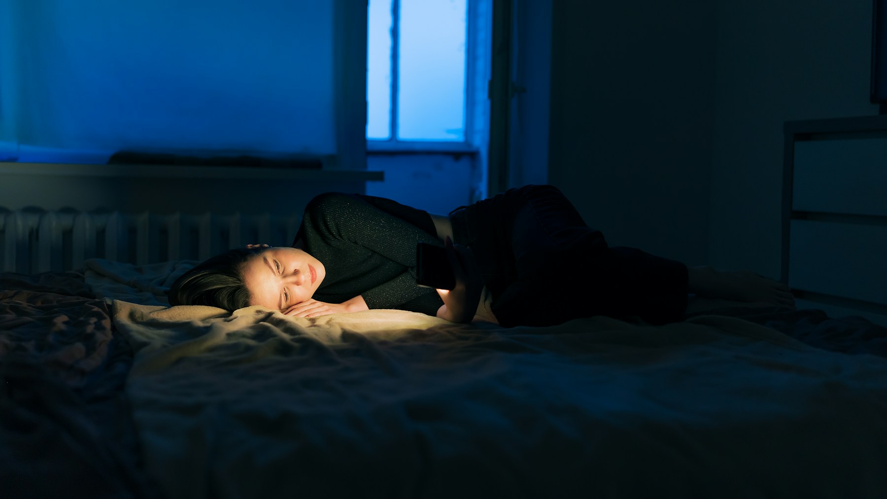 Person lying on a bed in a dark room